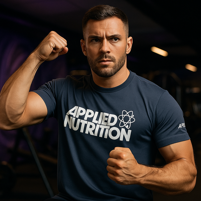 Man wearing Applied Nutrition t-shirt striking a strong pose in a gym with moody MSS purple lighting in the background