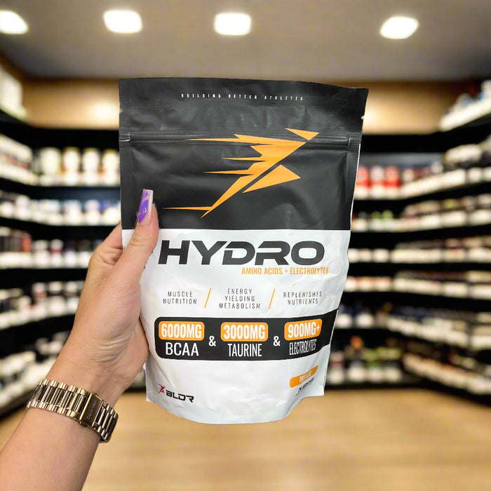 Close-up of BLDR Sports Hydro 360g) held up inside My Supplement Shop, clearly showing the front label in a Sports Nutrition setting.