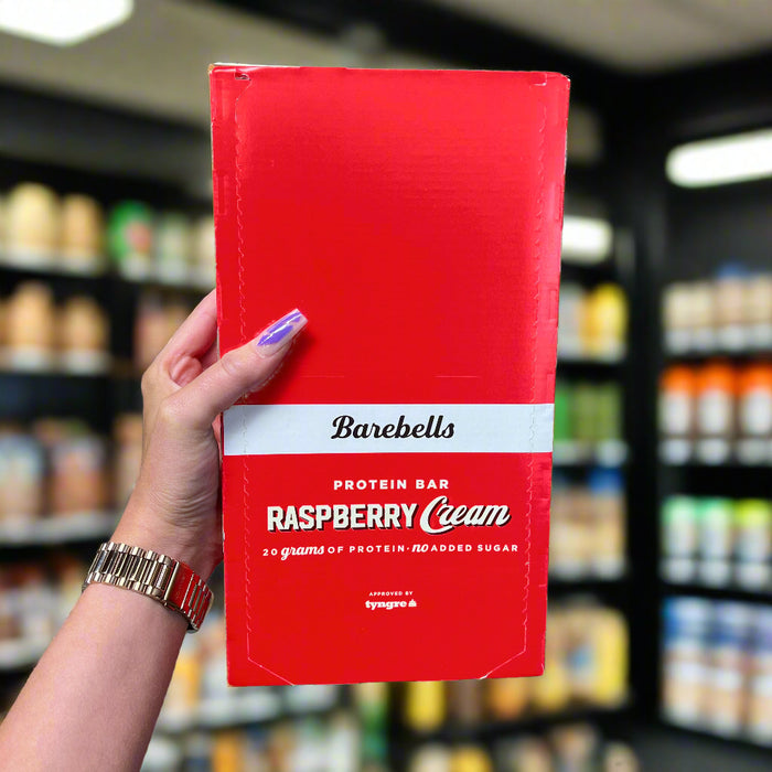 Close-up of (Barebells Protein Bars 12x55g) held up inside My Supplement Shop, clearly showing the front label in a Sports Nutrition setting.