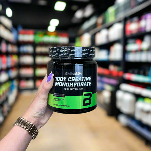 Close-up of (BioTechUSA 100% Creatine Monohydrate, Unflavoured 300g) held up inside My Supplement Shop, clearly showing the front label in a Sports Nutrition setting.