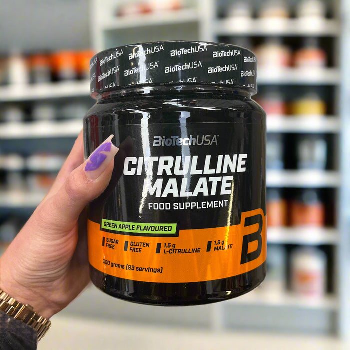 Close-up of (ioTechUSA Citrulline Malate, Green Apple - 300 grams) held up inside My Supplement Shop, clearly showing the front label in a Sports Nutrition setting.