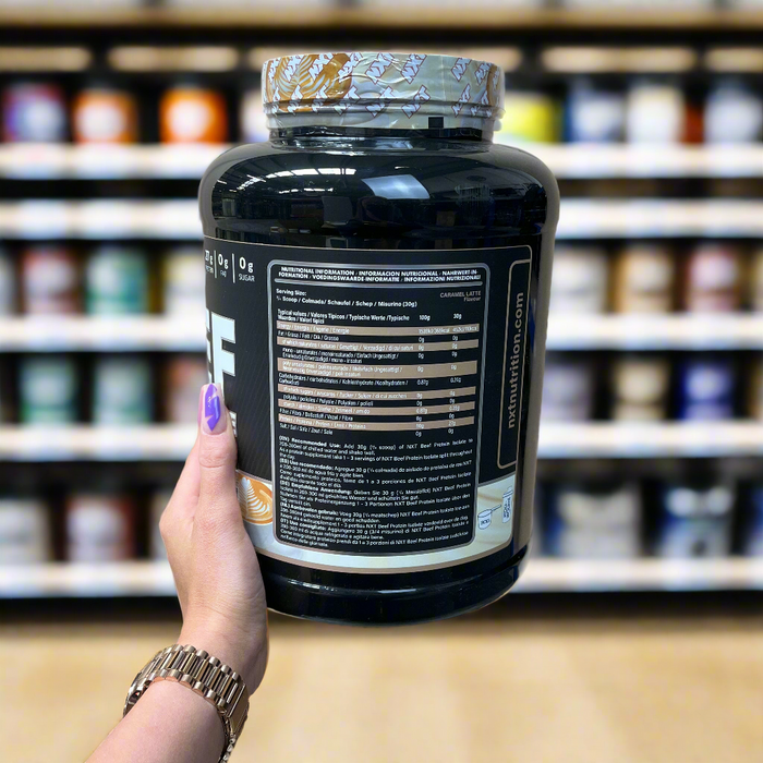 Close-up of (NXT Nutrition Beef Protein Isolate 1.8kg) held up inside My Supplement Shop, clearly showing Nutritional Values on the packaging in a Sports Nutrition setting.